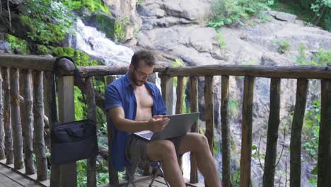 Office-worker-working-outdoors-in-forest-with-waterfall.
